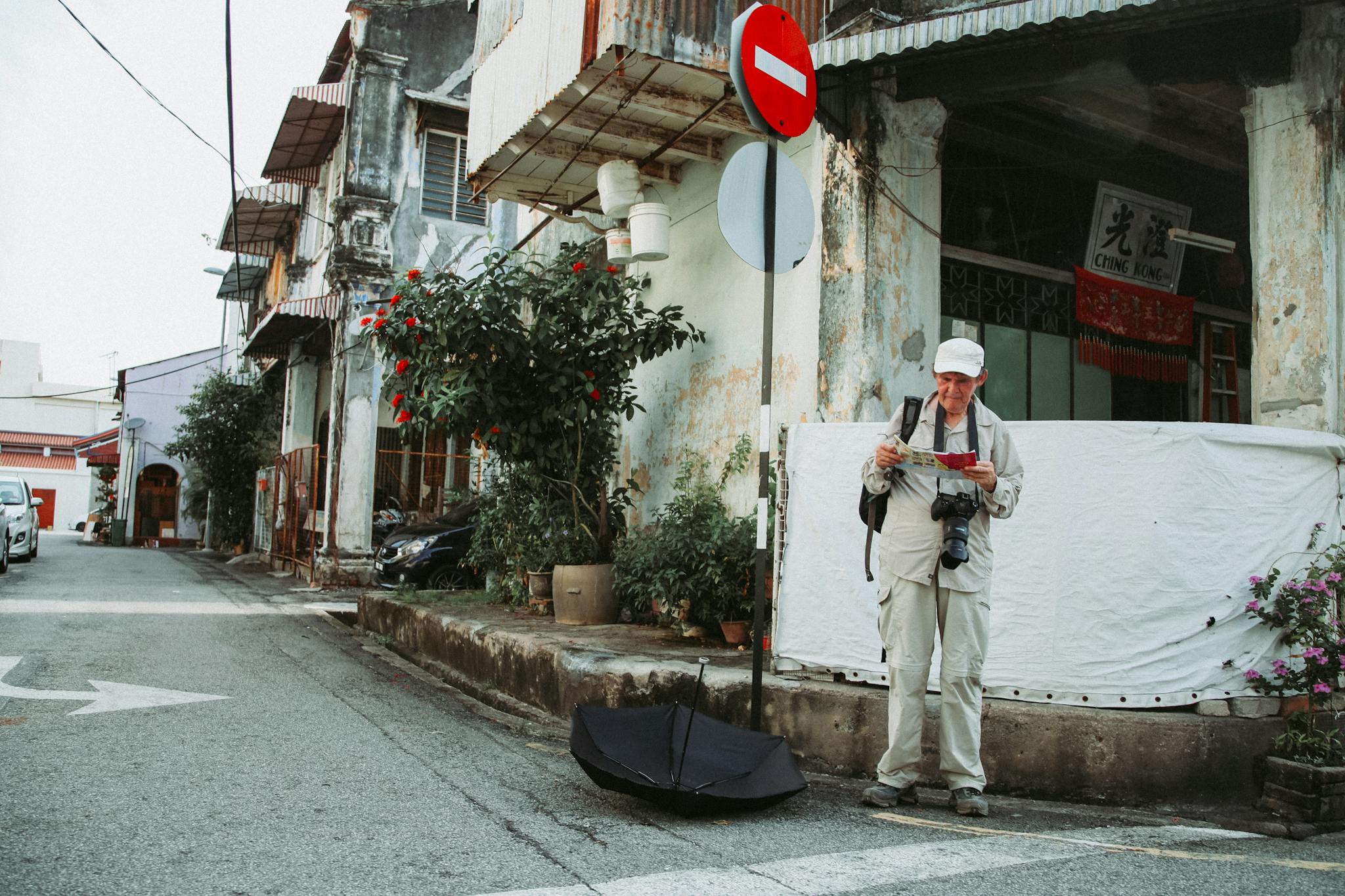 An elderly tourist with a camera and map exploring a historic city street.